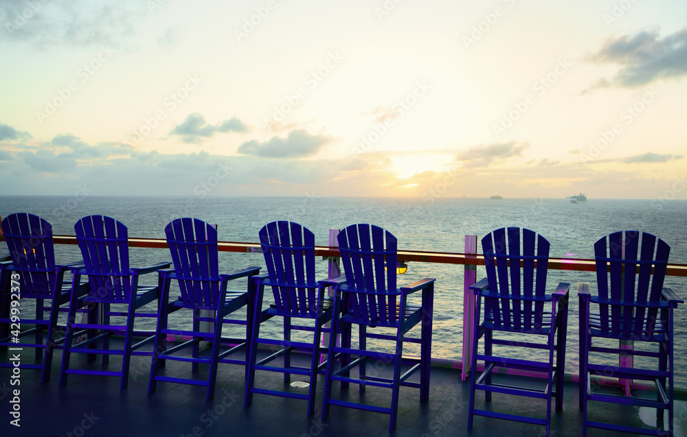 Wooden deck chairs on cruise ship. Beautiful sunset.