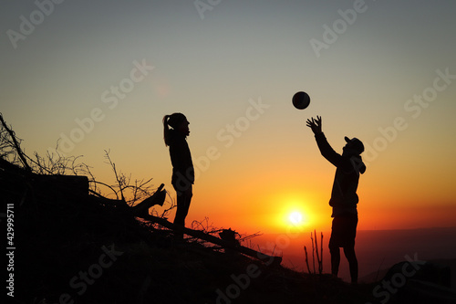 young couple playing volleyball together on top of a mountain at sunset and their dog obediently waits for them. Volleyball stroke. Overhead passing at Beskydy, czech republic