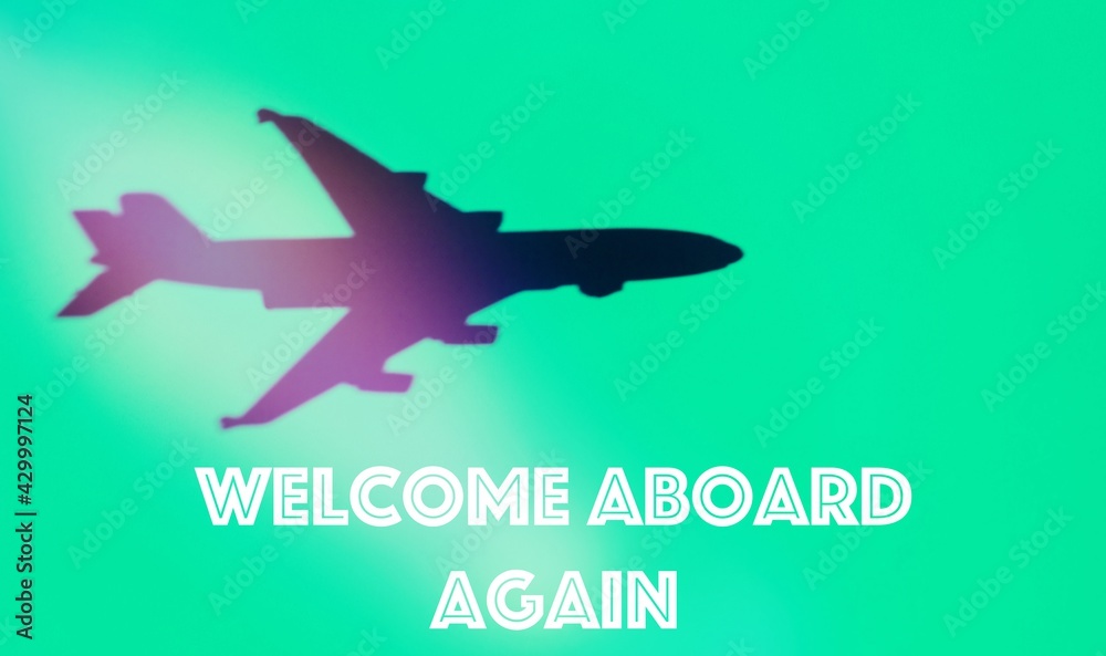 Shadow of a plane in a green background, with the text, welcome aboard again, concept of reopening .