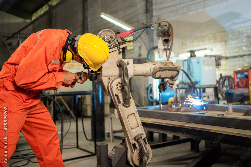 Engineer worker repair the arm robot machine. Preventive maintenance in factory. Using screwdriver to remove nut and look at electric system. Industrial, technology and innovation concept. Engineer worker repair the arm robot machine. Preventive maintenance in factory. Using screwdriver to remove nut and look at electric system. Industrial, technology and innovation concept.