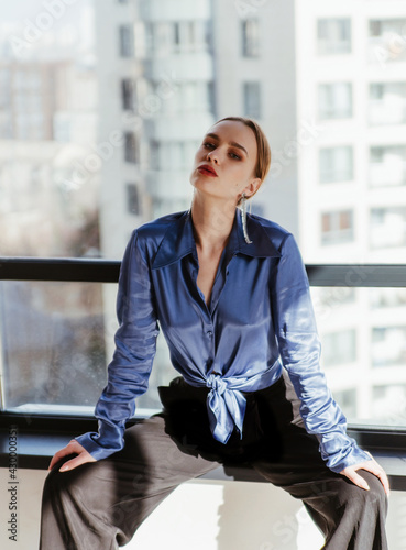 Tableau sur toile Stylish model in a blue satin blouse and black pants in modern studio posing
