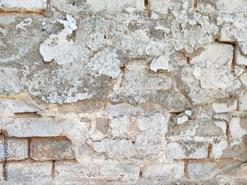 Vintage brick wall with peeled damaged plaster