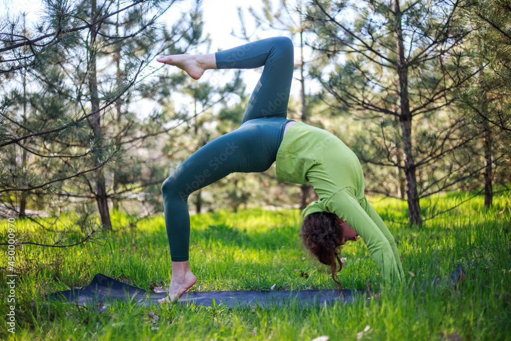 Girl doing yoga in fir park, fitness exercise outdoors, healthy lifestyle and freshness of pure nature Girl doing yoga in fir park, fitness exercise outdoors, healthy lifestyle and freshness of pure nature
