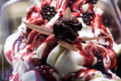 tub of cream ice cream and strawberry syrup with chocolate flowers in artistic way in an Italian ice cream shop to refresh