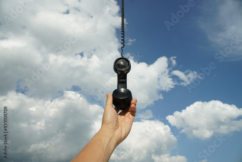 vintage black phone with line hanging from the sky. Conceptual photography talking to someone from above