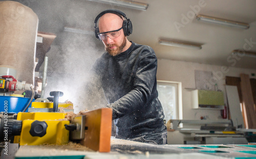 Carpenter working on woodworking saw machines in carpentry shop, industrial concept