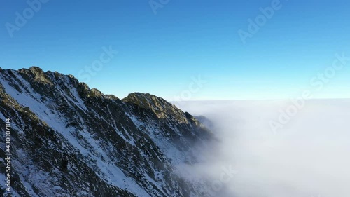 Flying over clouds and Fagaras mountains. Transfagarasan road in winter.