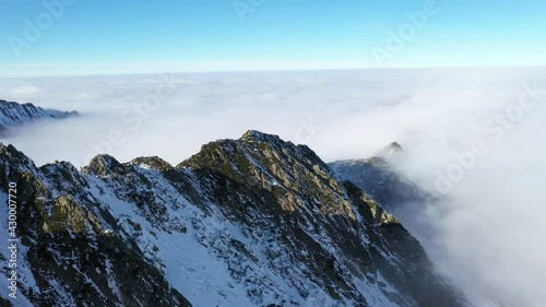 Flying over clouds and Fagaras mountains. Transfagarasan road in winter.