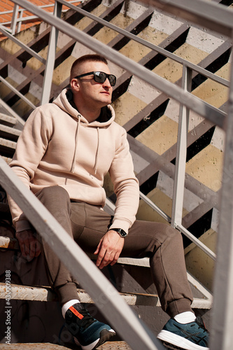 A young man sits on the steps in the city. Urban style. Lifestyle photo
