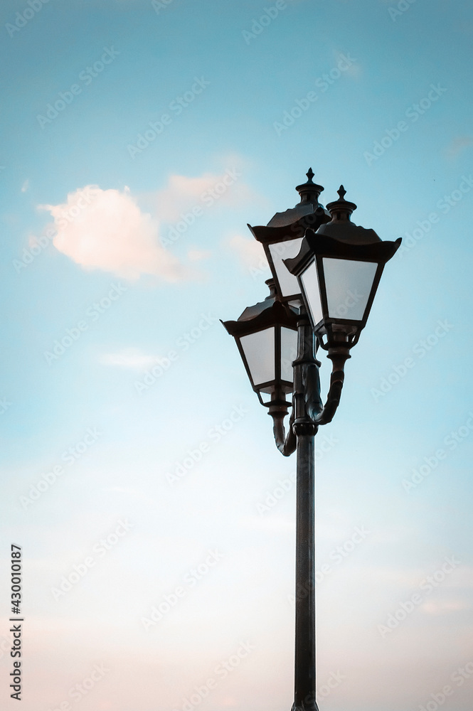 Beautiful old lantern on a background of blue sky. Vertical photography.