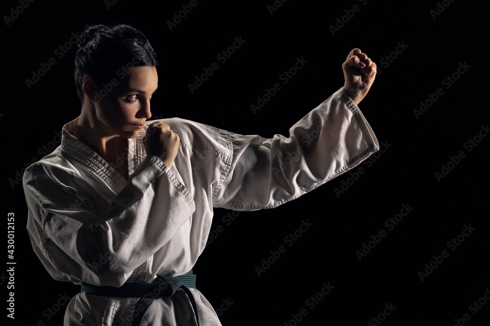 Young woman in kimono in fighting stance on a black background