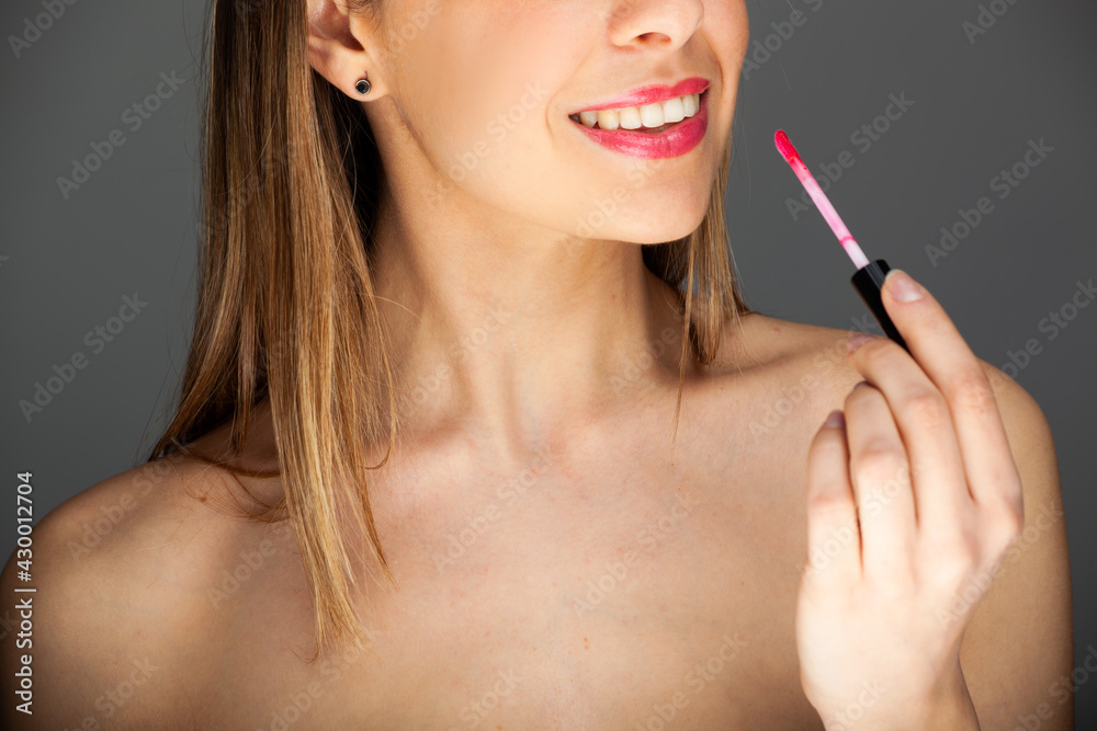 Fototapeta premium Beautiful charming woman applying lipstick