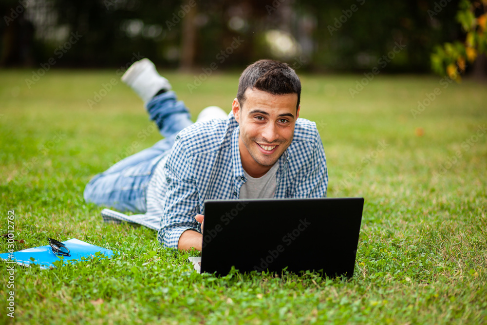 Student using laptop on the grass Student using laptop on the grass