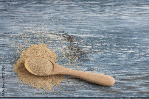 Dry instant yeast in a wooden spoon on a light background