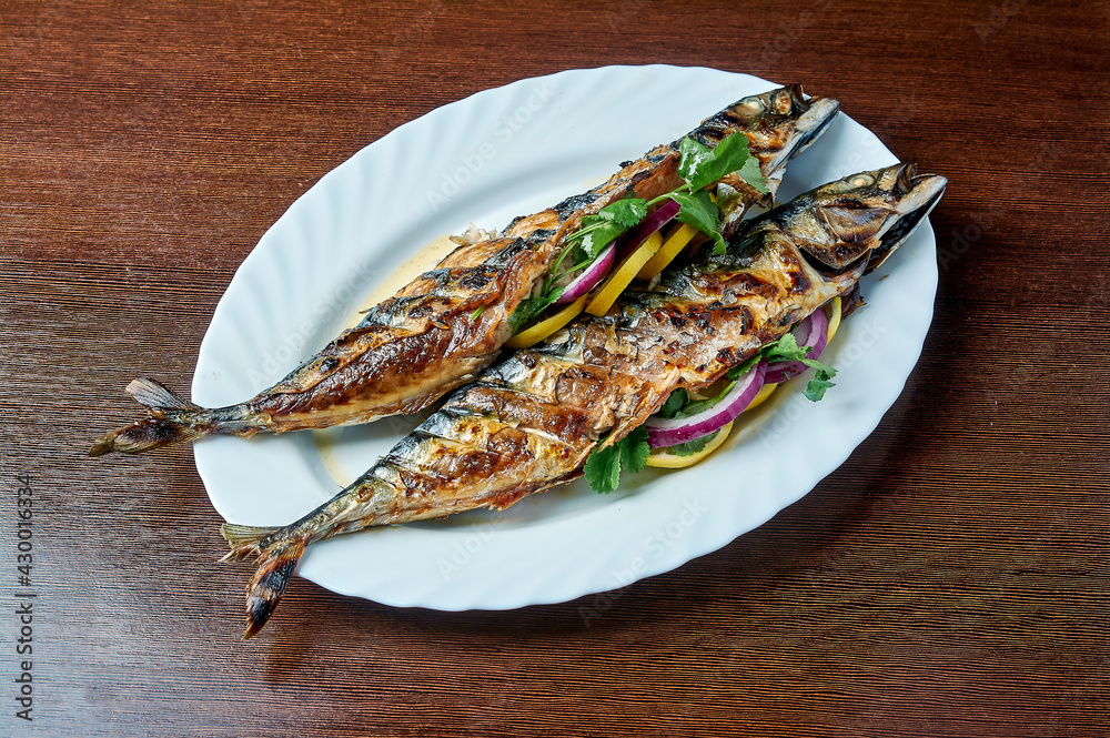 Mackerel baked on the grill lies on a white plate Mackerel baked on the grill lies on a white plate