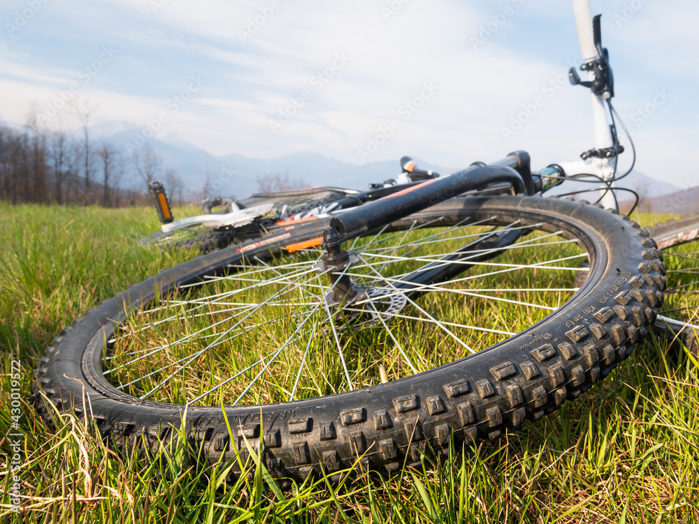 Mountain bike wheel close up. Mtb lying on the grass of alpine meadow. Wide angle view. Mountain bike wheel close up. Mtb lying on the grass of alpine meadow. Wide angle view.