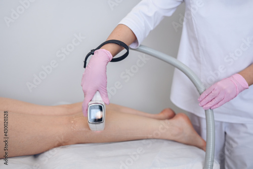 Laser epilation and cosmetology in beauty salon. Hair removal procedure. Laser epilation, cosmetology, spa, and hair removal concept. Beautiful blonde woman getting hair removing on legs