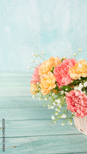 Fototapeta Naklejka Na Ścianę i Meble -  Pink basket with delicate carnations on a blue background