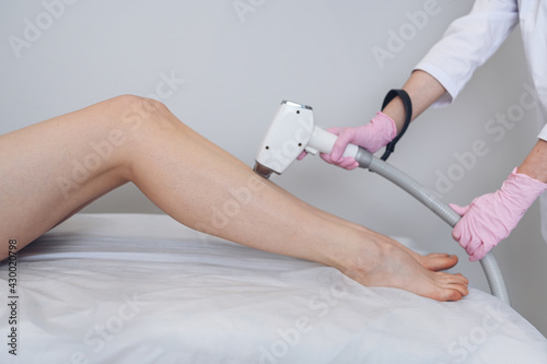 Laser epilation and cosmetology in beauty salon. Hair removal procedure. Laser epilation  cosmetology  spa  and hair removal concept. Beautiful blonde woman getting hair removing on legs