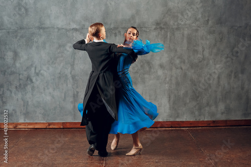 Fototapeta Young man and woman dancing waltz at ballroom.