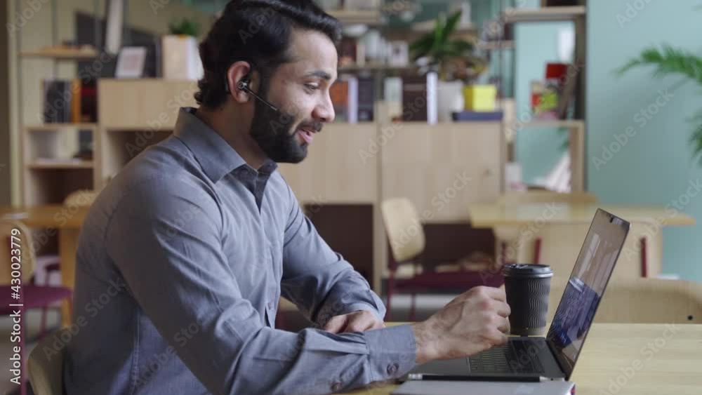 Indian business man wearing headset having virtual team meeting on video conference, call using laptop work from home office talking to diverse people group in remote teamwork online distance chat. Indian business man wearing headset having virtual team meeting on video conference, call using laptop work from home office talking to diverse people group in remote teamwork online distance chat.