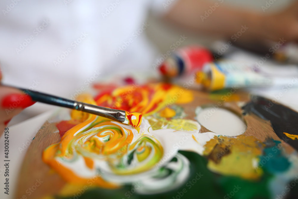 Fototapeta premium Close-up of paintbrush with mixed yellow and red paints