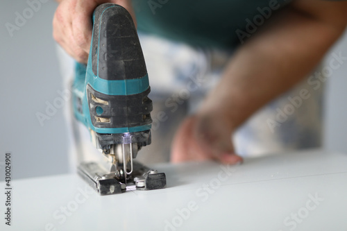 Close-up of qualified worker using electrical instrument for work with wood