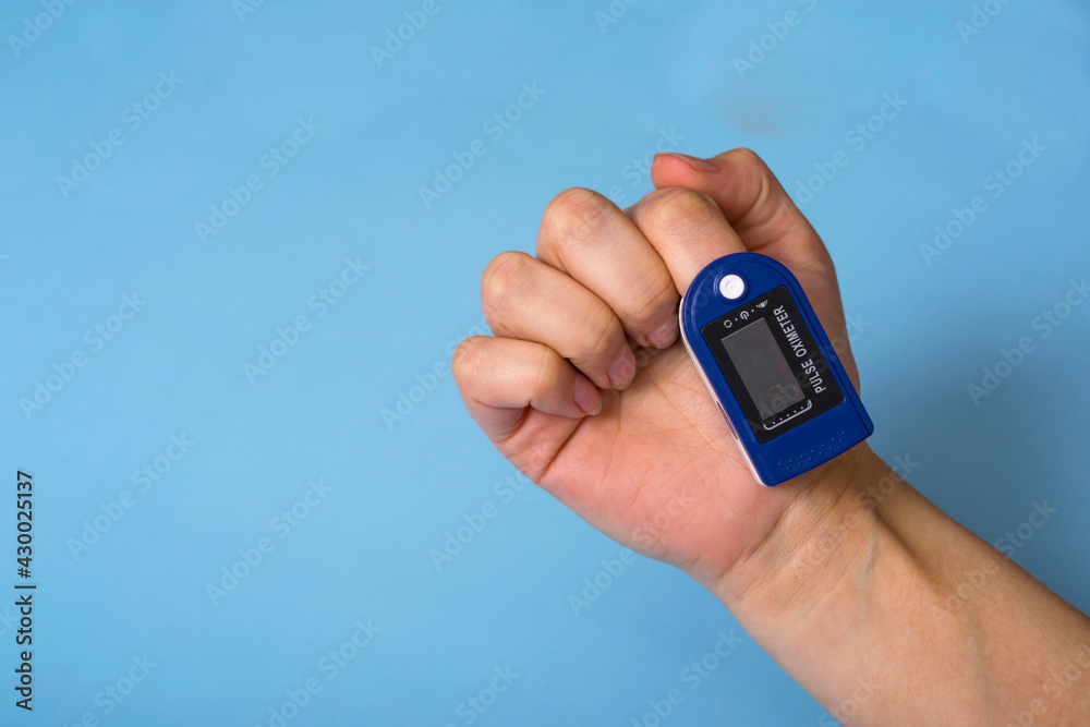 A pulse oximeter is on the woman's hand. A pulse oximeter used to measure heart rate and oxygen levels.. Covid-19 A pulse oximeter is on the woman's hand. A pulse oximeter used to measure heart rate and oxygen levels.. Covid-19