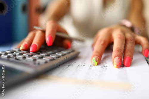 Womans hands with manicure press the calculator