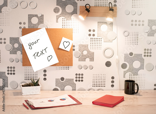 a comfortable workplace and a note board. notebook, charts and a cup are on the table
