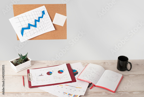 comfortable workplace. notebook, charts and a cup are on the table
