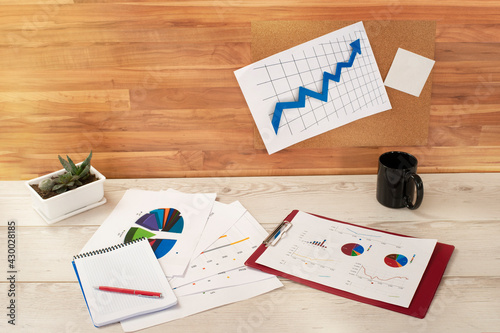 comfortable workplace. notebook, charts and a cup are on the table
