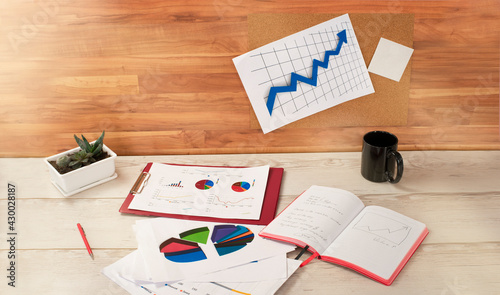 comfortable workplace. notebook, charts and a cup are on the table
