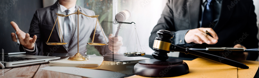 Justice and law concept.Male judge in a courtroom with the gavel, working with, computer and docking keyboard, eyeglasses, on table in morning light Justice and law concept.Male judge in a courtroom with the gavel, working with, computer and docking keyboard, eyeglasses, on table in morning light