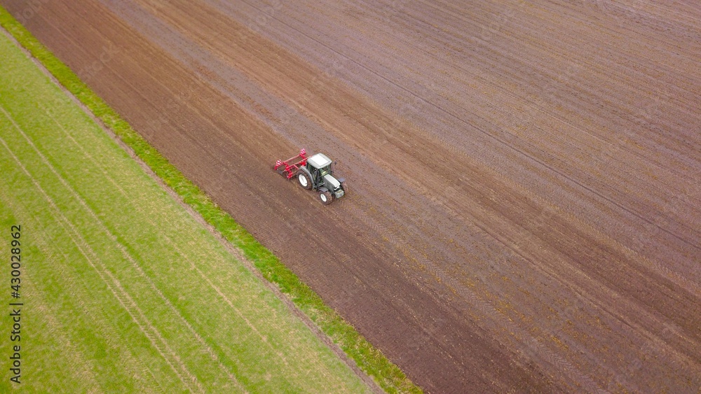 Fototapeta premium Traktor mit Gruber bewirtschaftet ein Acker, Landwirtschaft aus der Vogelperspektive