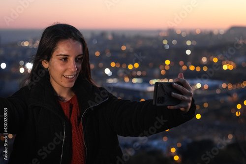 A young pretty girl doing a selfie with Barcelona citty on the background photo