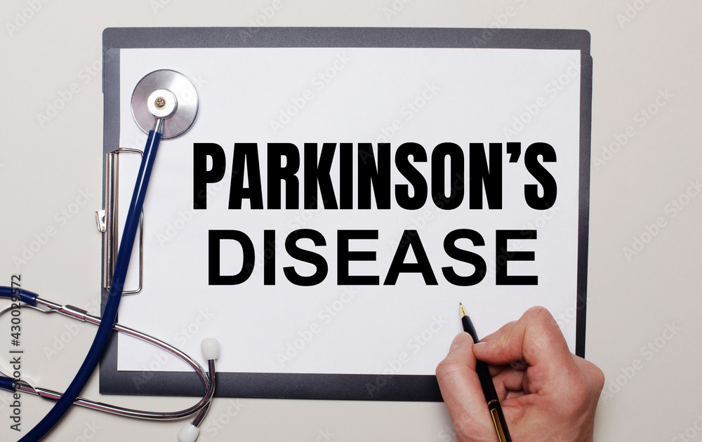 On a light background, a stethoscope and a sheet of paper, on which a man writes PARKINSON IS DISEASE. Medical concept