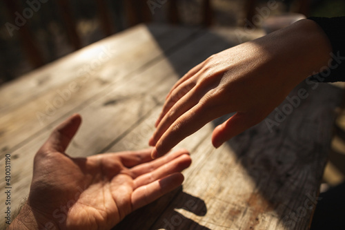 Hugging Hands of Lovers on Wooden Table in Sunny Day