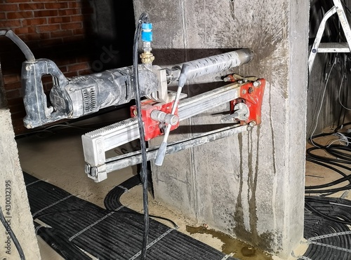 using a diamond drill on a wall-mounted machine, a hole is drilled in monolithic concrete for an electric cable and a socket with a water supply in the basement of a residential building