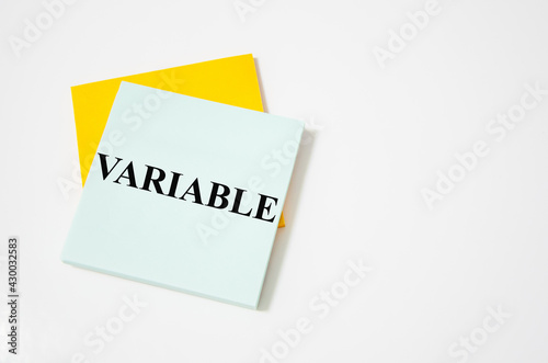 the variable text written on a white notepad with colored pencils and a yellow background