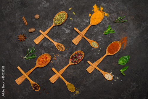 Variety of spices in wooden spoons on black background. Set of spices and herbs.