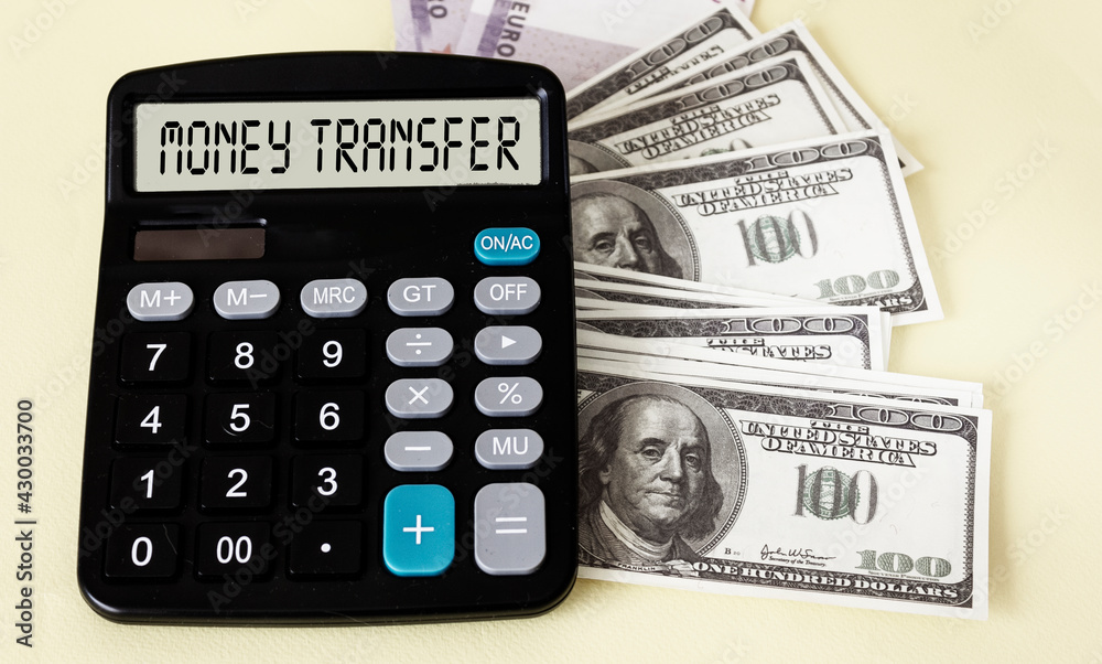 Calculator with text on the display MONEY TRANSFER, next to the banknotes of dollars and euros on a yellow background. Calculator with text on the display MONEY TRANSFER, next to the banknotes of dollars and euros on a yellow background.