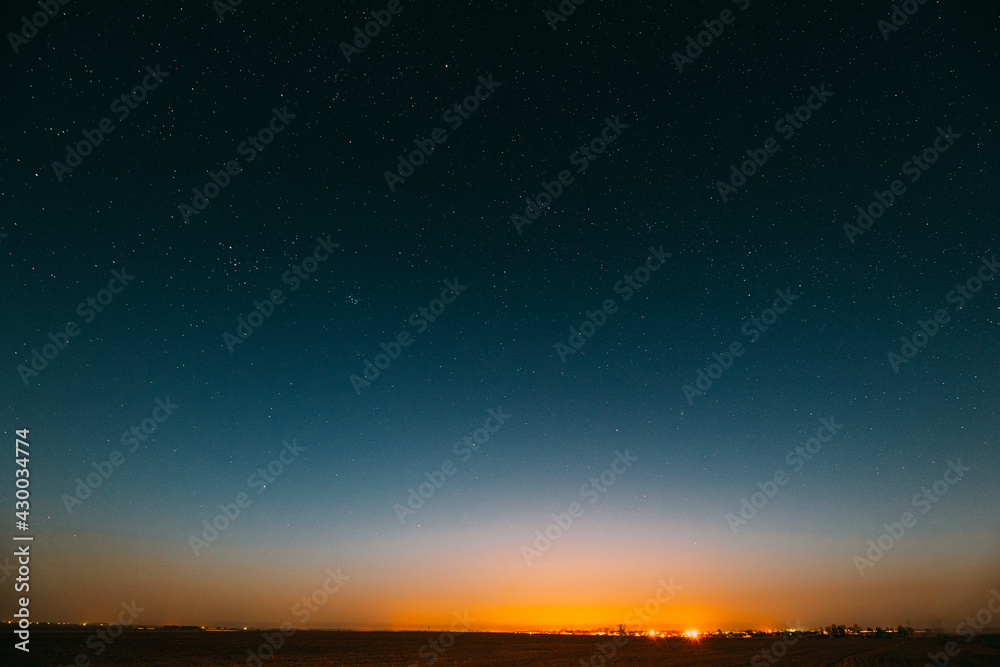 Night Starry Sky Over Yellow Sunset Or Sunrise Lights. Night Glowing Stars. Dark Night Starry Sky Over Ground In Warm Yellow Colors. Copyspace Space Abstract Landscape Background