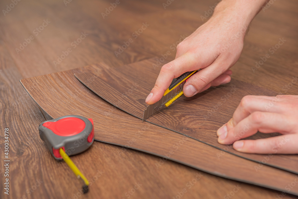 DIY vinyl flooring. Easy installation and cutting with a knife, Master cuts  vinyl plank before installation, brown heated floor. Copy space Stock-Foto  | Adobe Stock