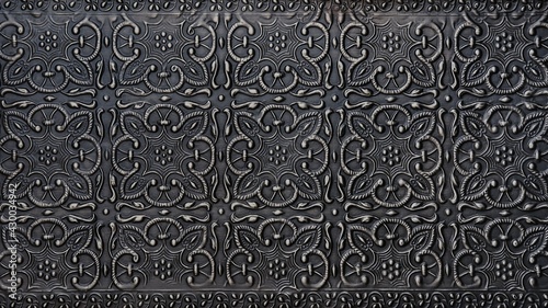 Traditional islamic rhythmic arabesque pattern in form of embossing on metal. Textured black silver metal backdrop with intricate carved interlace foliage and flowers elements, decoration chasing art.