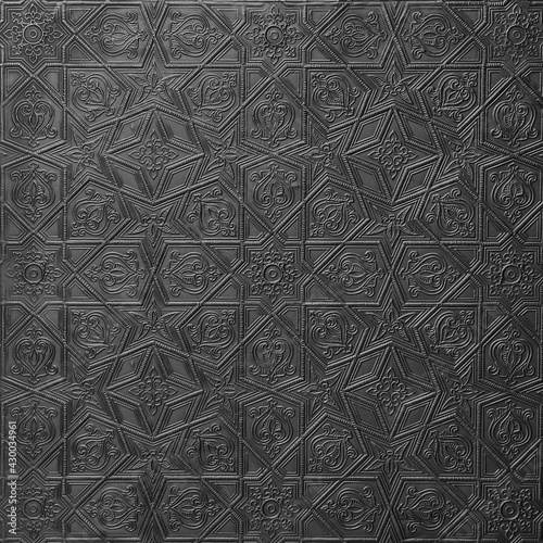Traditional islamic rhythmic arabesque pattern in form of embossing on metal. Textured black silver backdrop with geometric  intricate relief interlace lines,flowers elements. Decorative chasing art.