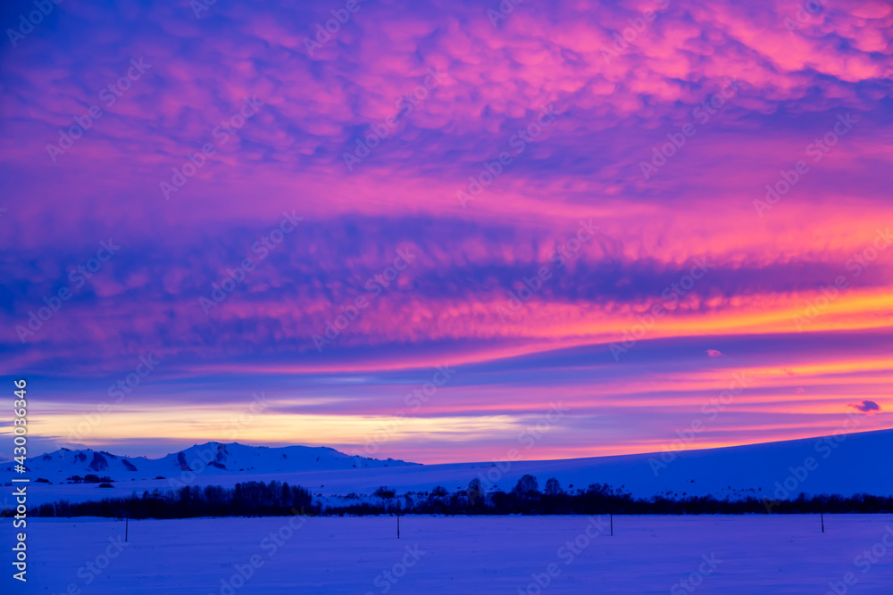Winter landscape with mountains during amazing vivid saturated beautiful sunset sky in pink, purple and blue colors. Sunset background.