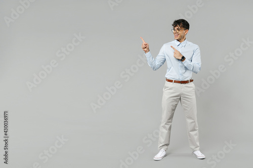 Full length fun young successful employee business latin man corporate lawyer wear classic white shirt glasses point index finger aside on workspace copy space area isolated on grey background studio.