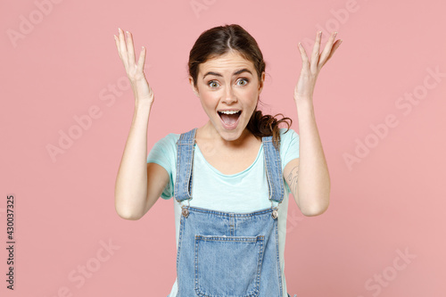 Young sad angry indignant expresive stressed nervous caucasian woman in denim clothes blue tshirt spread hands scream shout isolated on pastel pink background studio portrait People lifestyle concept photo