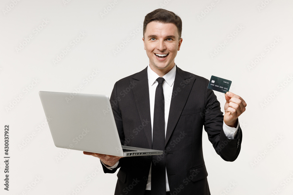 Young employee business corporate lawyer man 20s wear classic formal black grey suit shirt tie work in office hold laptop pc computer credit bank card book online isolated on white background studio Young employee business corporate lawyer man 20s wear classic formal black grey suit shirt tie work in office hold laptop pc computer credit bank card book online isolated on white background studio